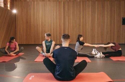 A group of adults practicing yoga and stretching on mats in a wooden panelled room.
