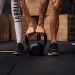A man and woman engaging in CrossFit training with a kettlebell at an indoor gym in Brazil.